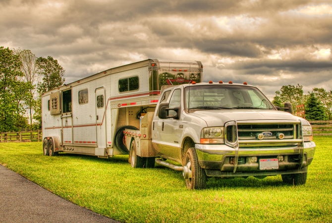 Colorful artistic scene showing horse trailer and truck on a grass parkway on a cloudy day.
