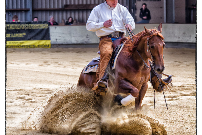 Reining horse and rider in action coming to a sudden stop.