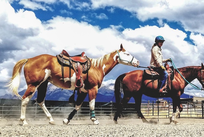 Julie Goodnight riding her horse Annie and ponying Gunner.