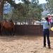 Julie Goodnight demonstrating techniques of training horses in arena as studens look on.