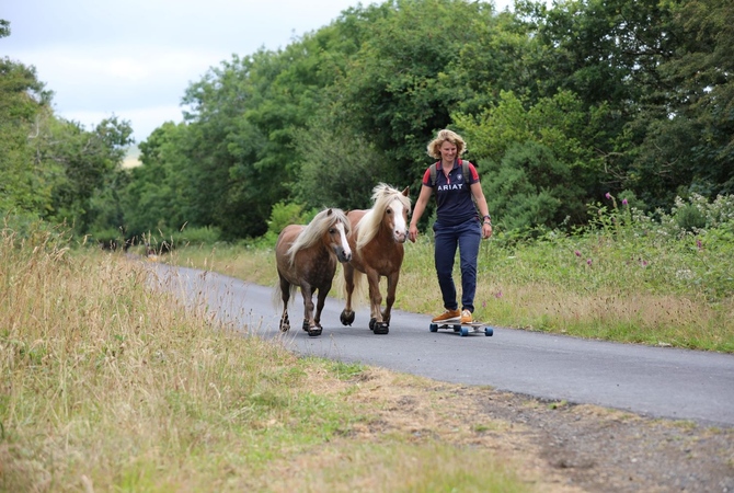 Emma Massingale skateboards  on a country road with her two miniature horses wearing their Cavallo hoof boots.