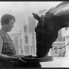 Dorothy Brooke holding a feeding pan for a warhorse.