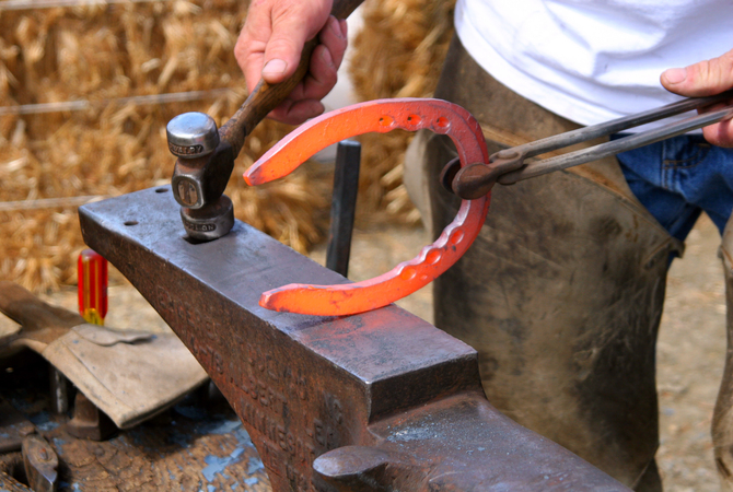 Farrier at work on a red hot customized horse shoe.