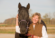 Happy woman caring for her horse.