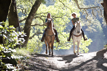 Two women riding horses on scenic trail.
