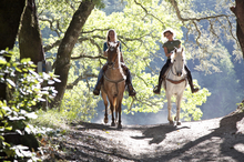 Two women enjoying a ride on a sunlit mountain trail.