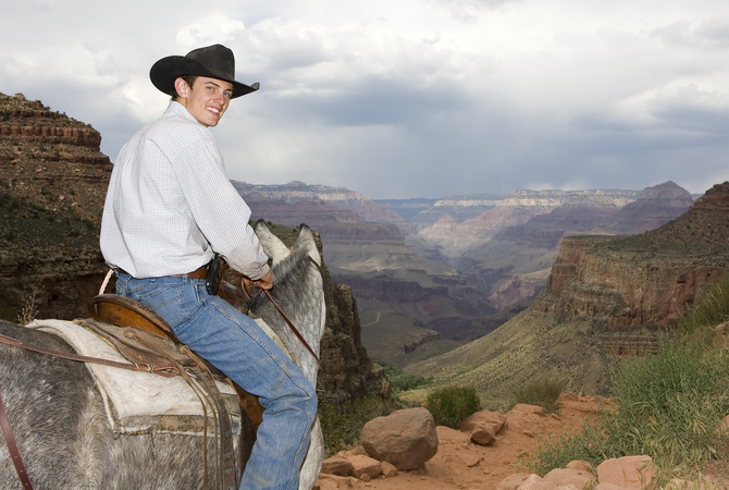 Young man on horse enjoying scenic views of Grand Canyon.