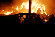 Silhouetted watchers as a barn burns.