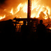 Silhouetts of people watching as horse barn burns to the ground.