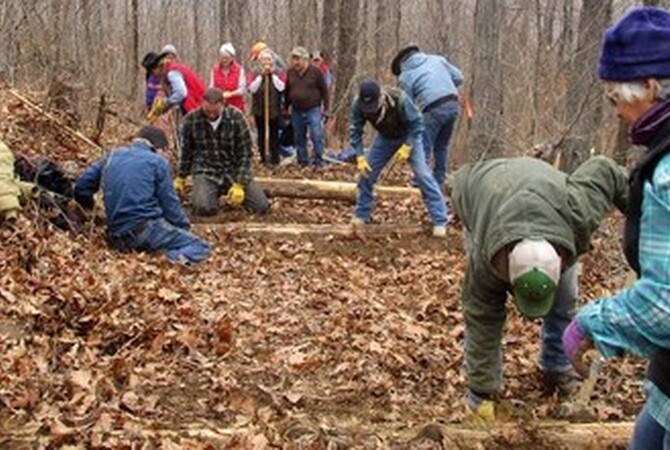 Back Country Horsemen working to build horse trail in a wooded area.