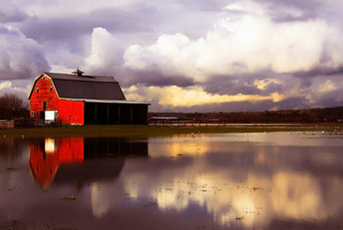 Stormy weather approaching red barn in country setting.