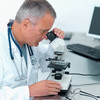 Researcher looking through microscope to examine disease samples.