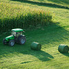 Harvesting hay with tractor and equipment making it into large, round bales.