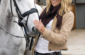 Woman getting horse ready for training by studying his reactions.