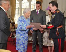 Colonel Perez receiving certificate from Queen Elizabeth accompanied by Monty Roberts